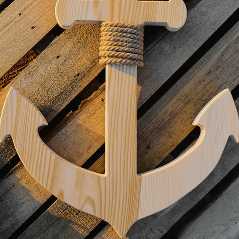 Drewniana kotwica dekoracyjna na tle drewnianych desek.
