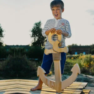 Chłopiec z drewnianą kotwicą na tle natury