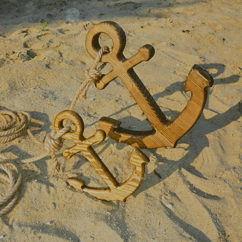 Dwie drewniane kotwice na piasku z liną.