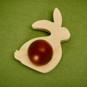 Drewniana ozdoba wielkanocna w kształcie królika z jajkiem.