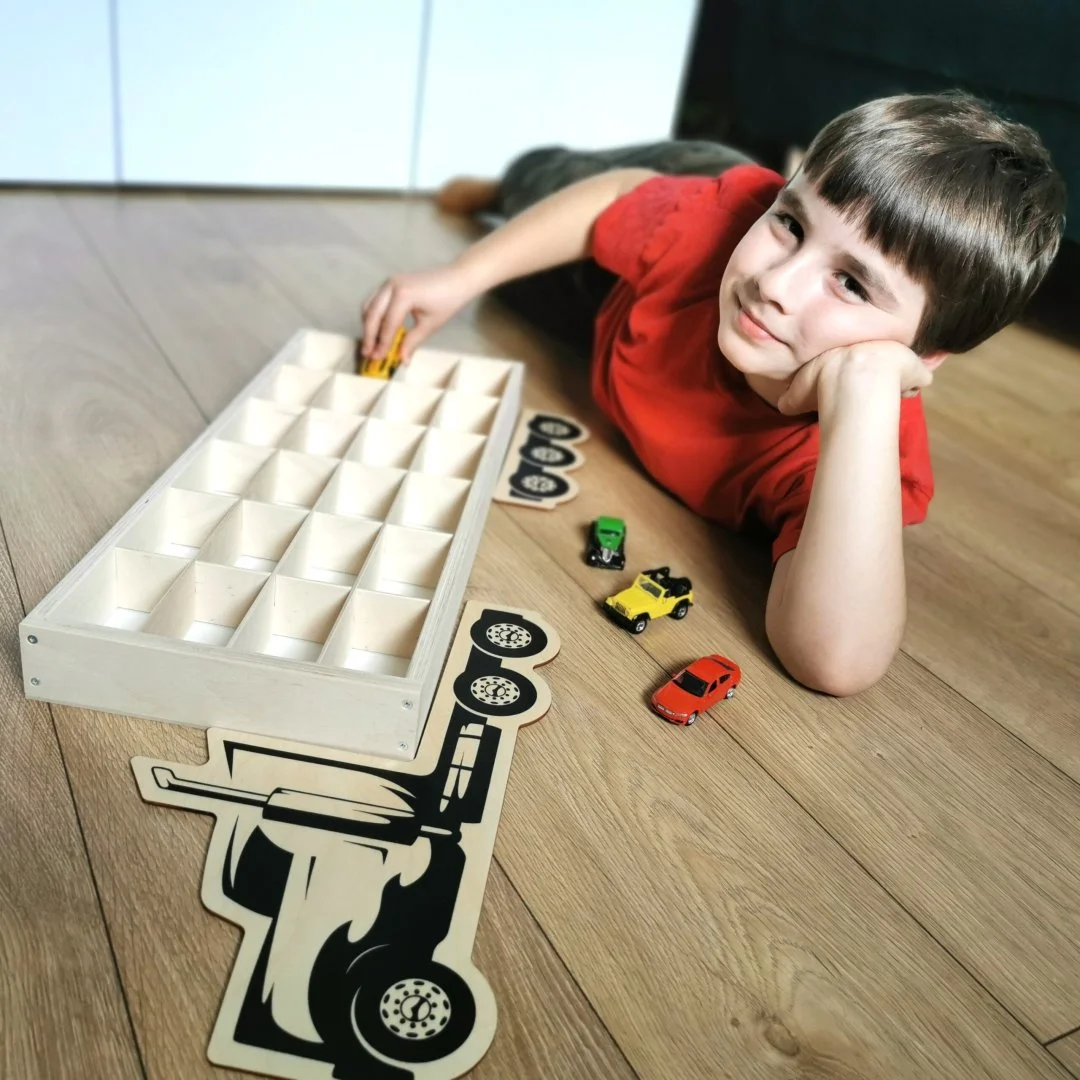 Chłopiec bawiący się małymi samochodzikami na podłodze.