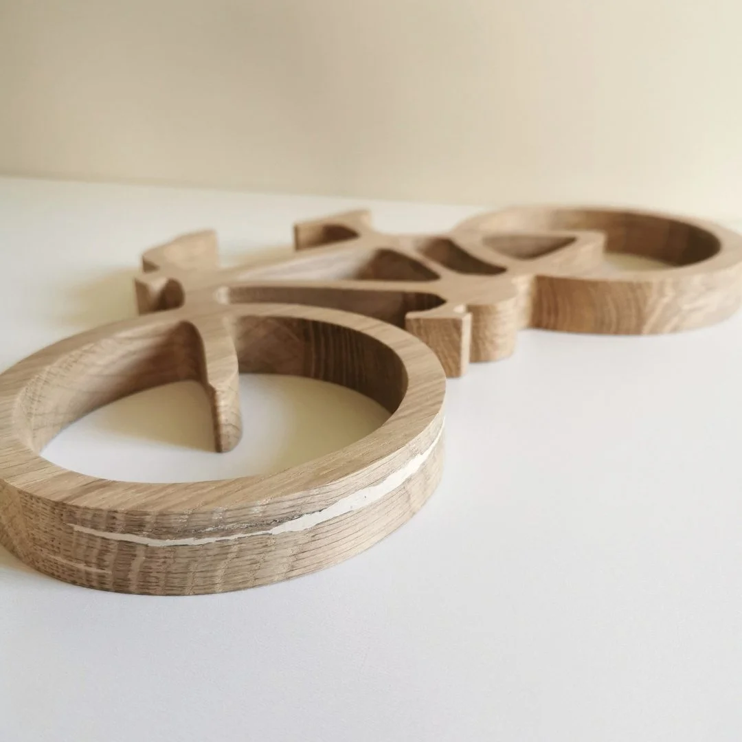 Drewniana ozdoba w kształcie roweru na białym tle.