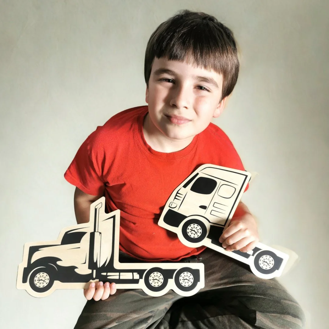 Dziecko trzymające drewniane zabawki ciężarówek.
