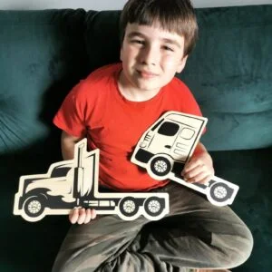 Chłopiec trzymający drewniane zabawki ciężarówek