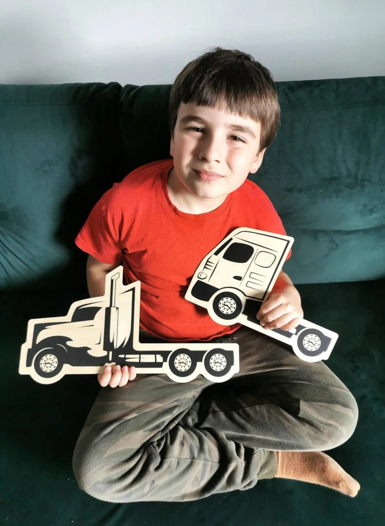 Chłopiec trzymający drewniane zabawki ciężarówek
