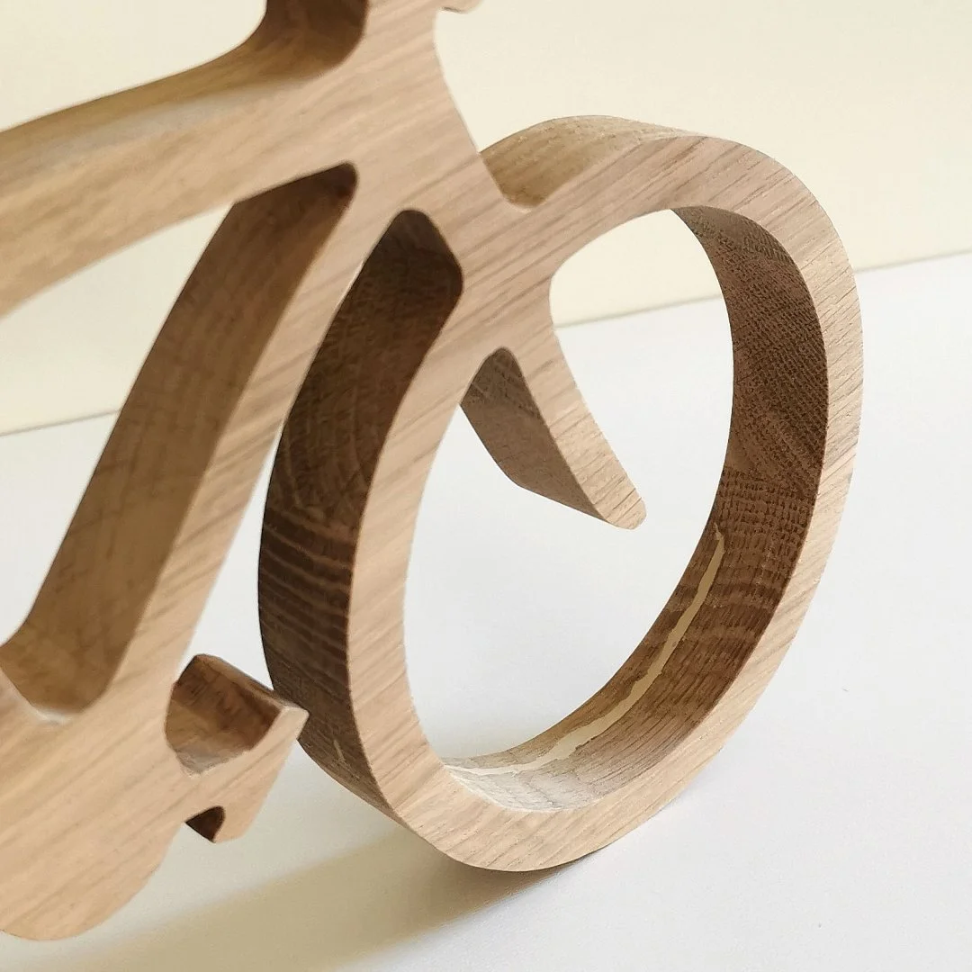 Drewniany model roweru z wyciętym kształtem koła.