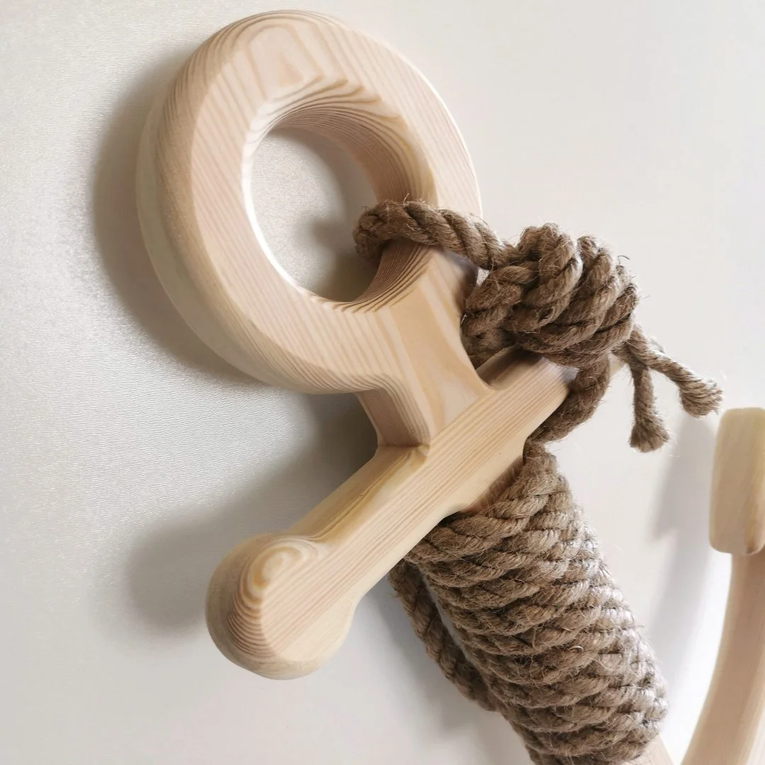 Drewniany wieszak w kształcie kotwicy z liną marynistyczną.