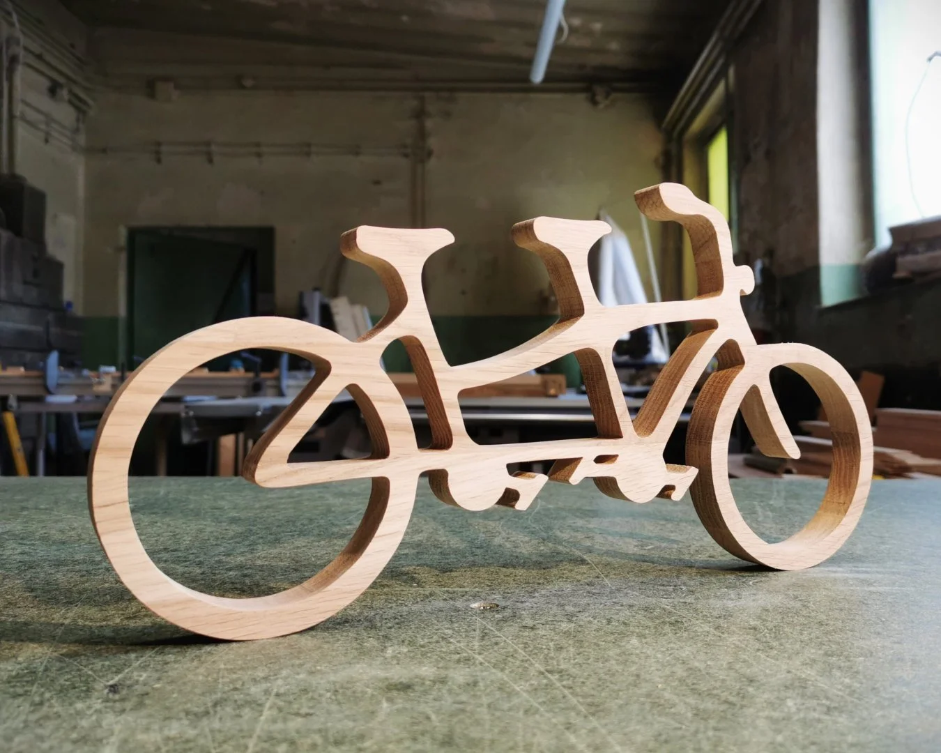 Drewniana rzeźba tandemu na stole warsztatowym.