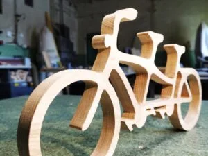 Drewniany model roweru tandemowego na stole warsztatowym.