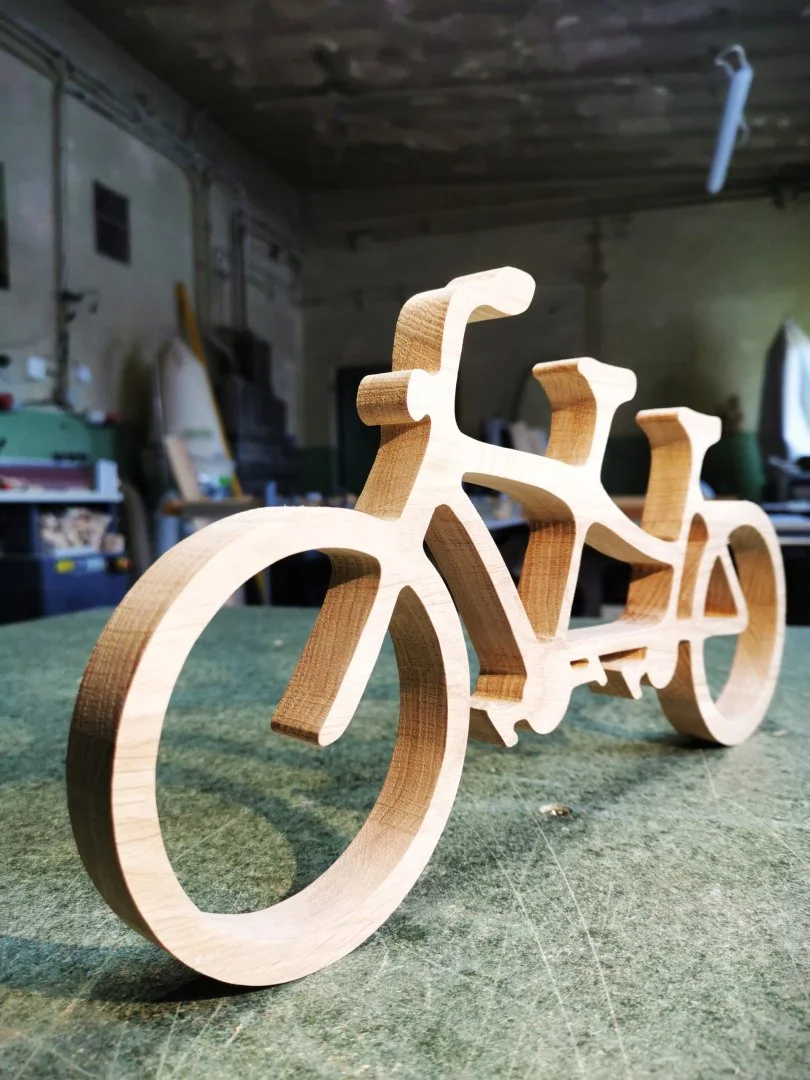 Drewniany model roweru tandemowego na stole warsztatowym.