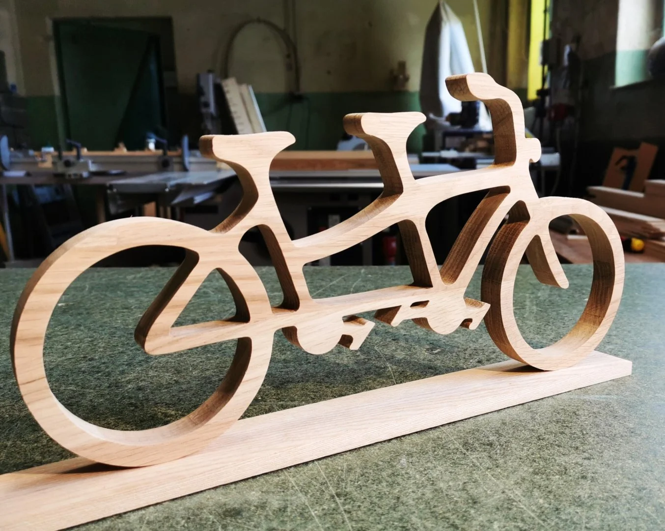 Drewniana figurka roweru tandemowego na stole warsztatowym.
