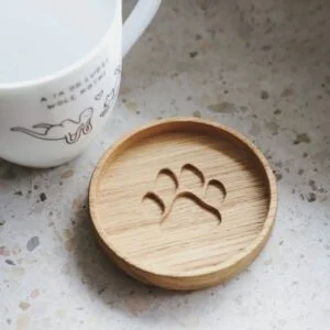 Drewniana podkładka pod kubek z wycięciem w kształcie łapki.