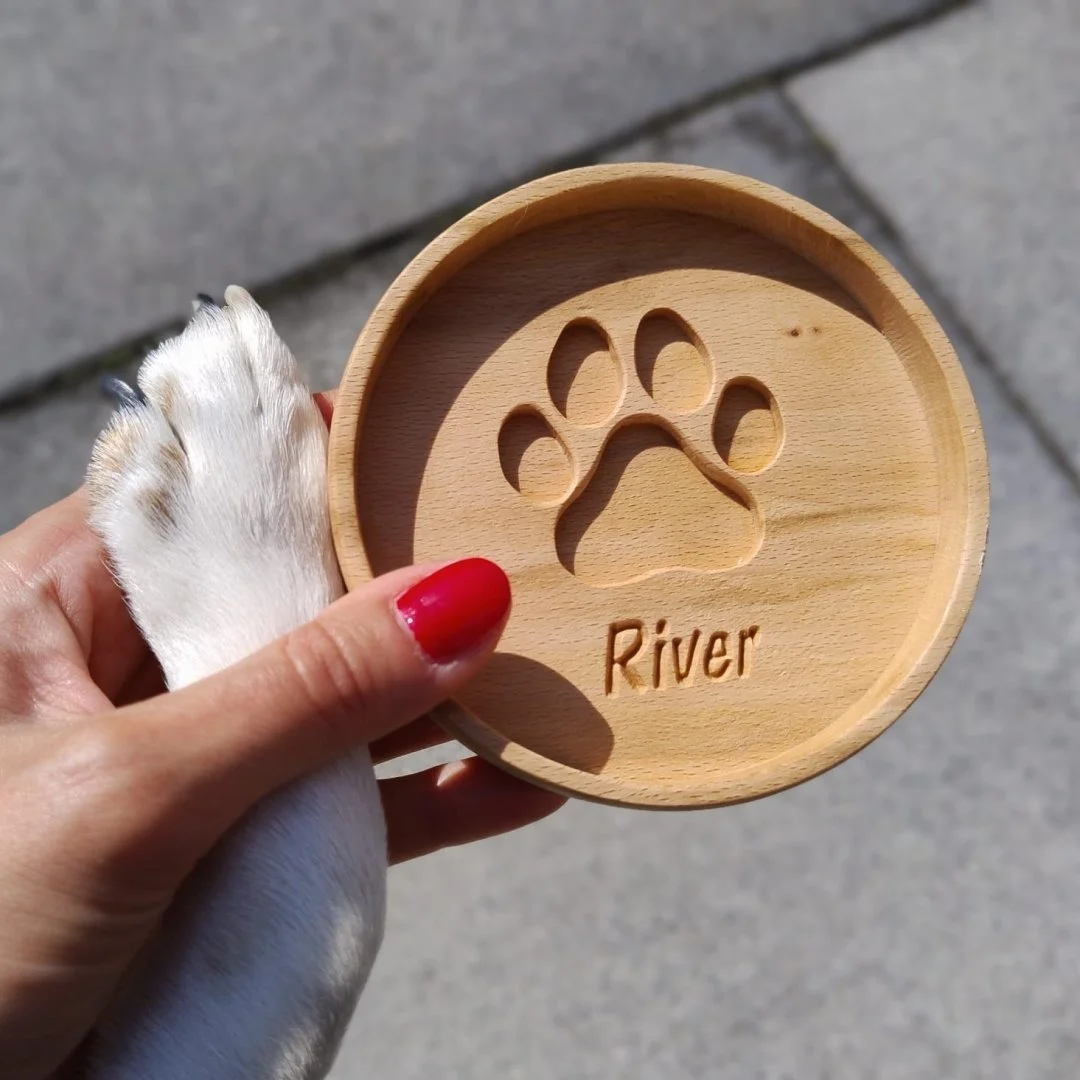 Drewniana podkładka z wyciętym śladem łapy i napisem 'River'.