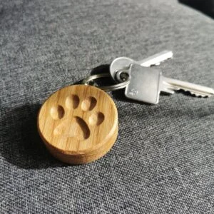 Drewniany breloczek z odciskiem łapki na tle kluczy.