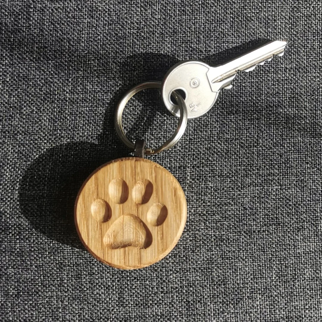 Drewniany breloczek z odciskiem łapki na tle kluczy.