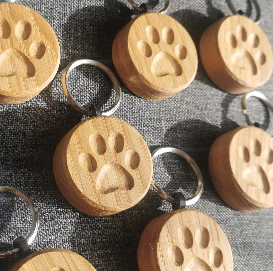 Drewniany breloczek z odciskiem łapki psa lub kota.