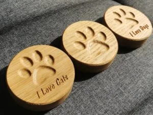 Drewniane otwieracze z magnesem z wyciętymi łapkami i napisami I Love Cats i I Love Dogs.
