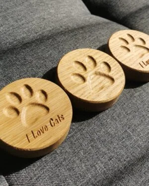 Drewniane otwieracze z magnesem z wyciętymi łapkami i napisami I Love Cats i I Love Dogs.