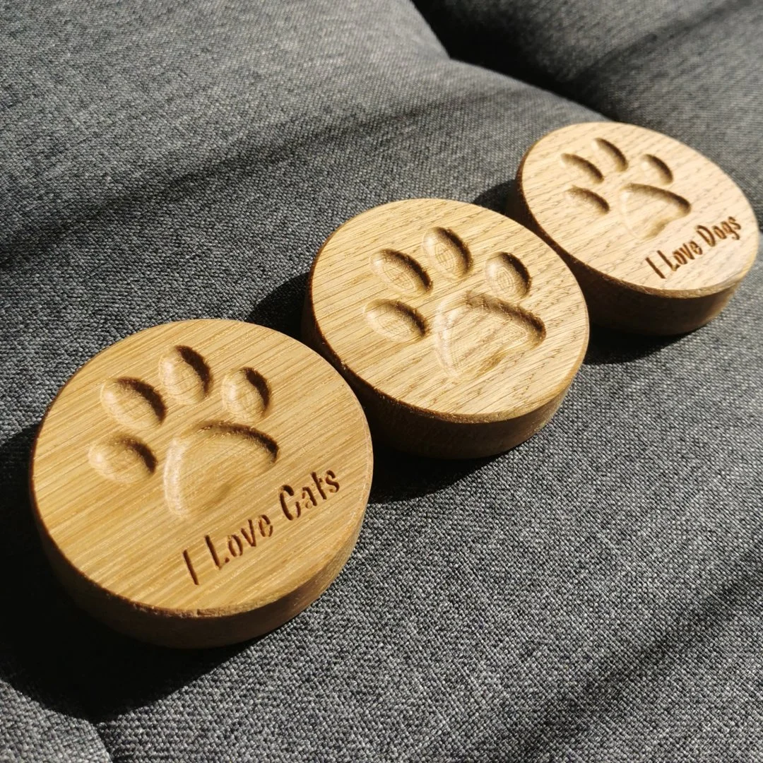 Drewniane otwieracze z magnesem z wyciętymi łapkami i napisami I Love Cats i I Love Dogs.