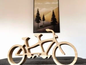 Drewniany rower tandem na tle obrazu z górami.