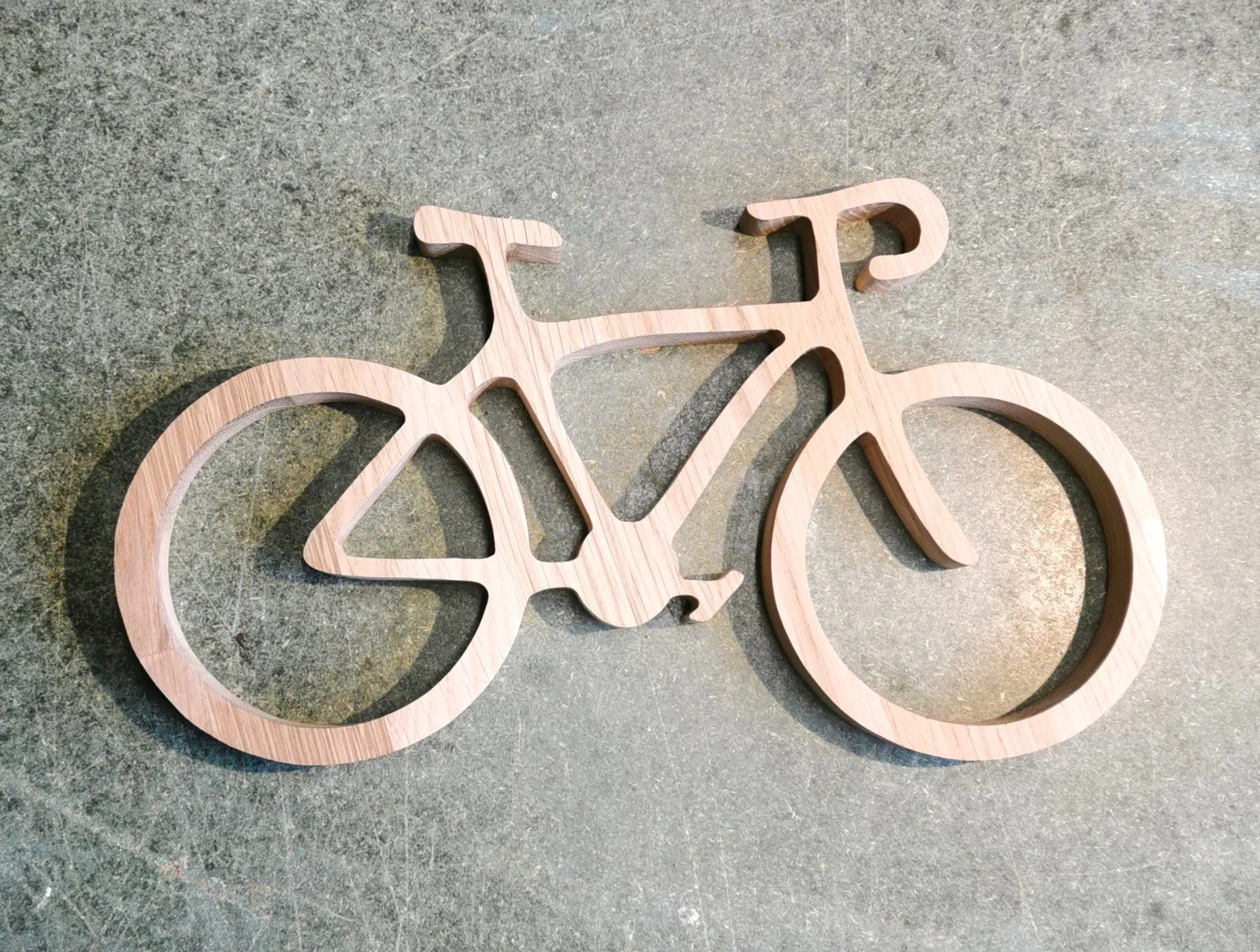 Drewniana dekoracja w kształcie roweru na szarym tle.