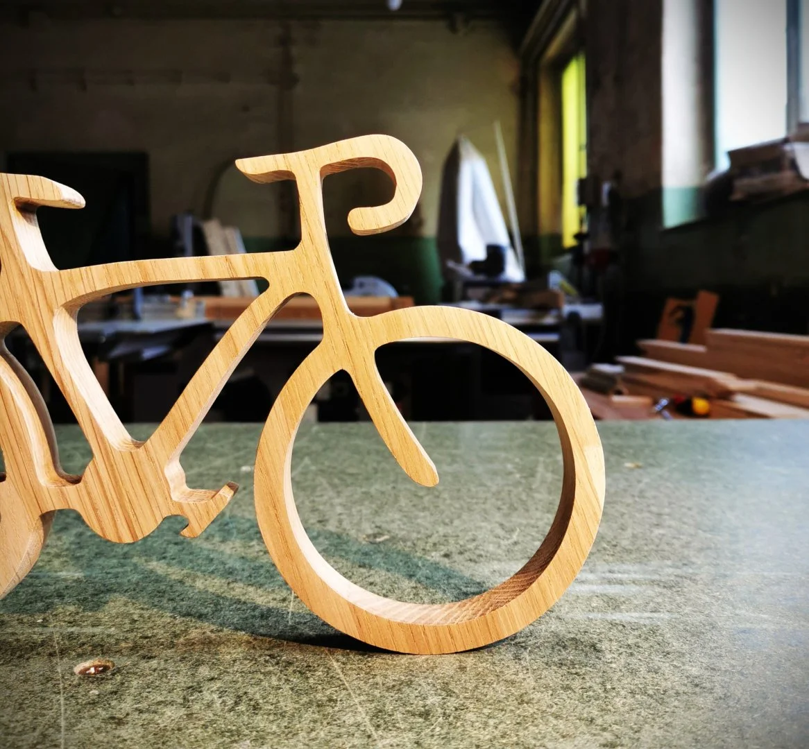 Drewniana dekoracja w kształcie roweru na stole warsztatowym.