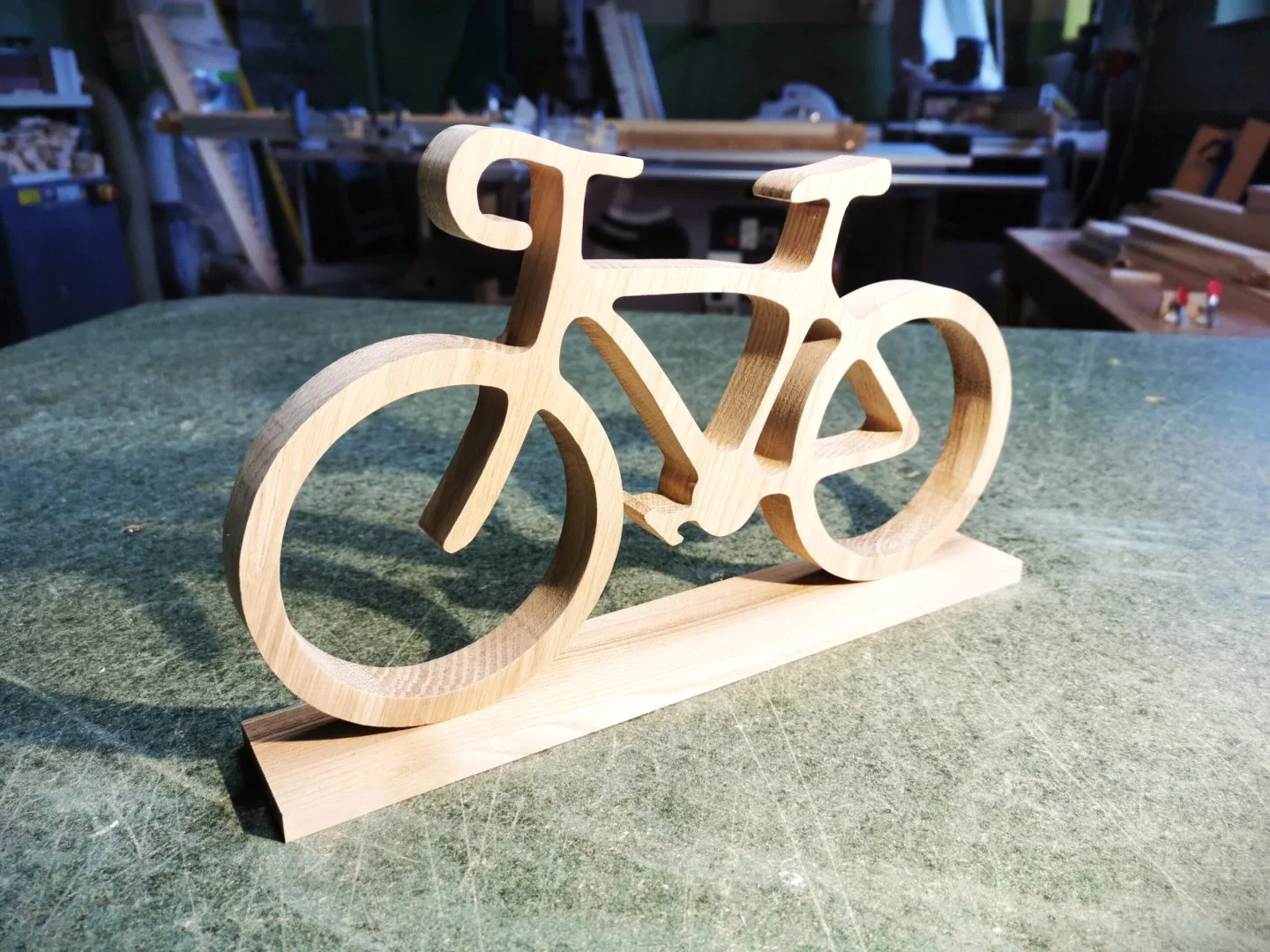 Drewniana rzeźba roweru na stole warsztatowym.