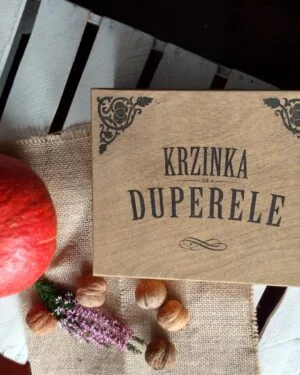Drewniane pudełko z napisem 'Krzinka na duperele' obok dyni i orzechów.