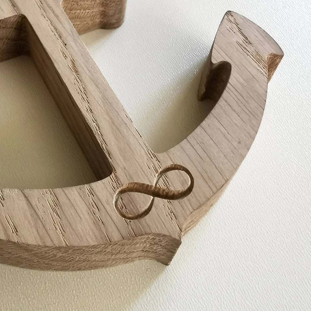 Drewniana kotwica z symbolem nieskończoności na białym tle.