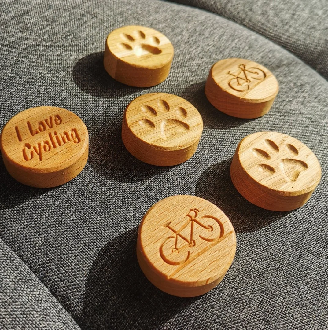 Drewniane magnesy z motywami roweru i psiej łapy.