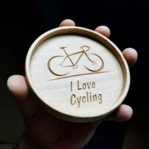 Drewniana podstawka z wygrawerowanym rowerem i napisem 'I Love Cycling'.