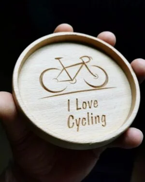 Drewniana podstawka z wygrawerowanym rowerem i napisem 'I Love Cycling'.